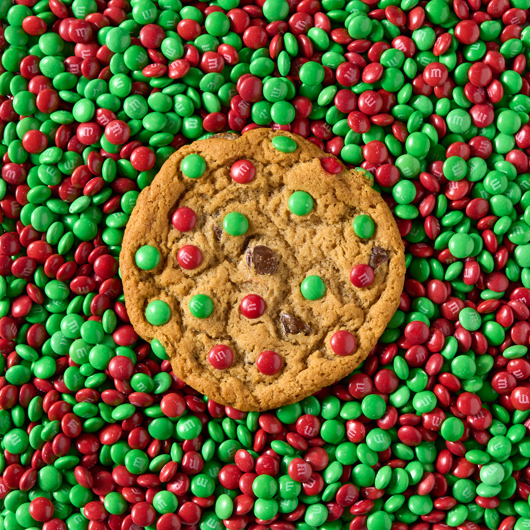 Original Chocolate Chip cookie surrounded by red and green M&MS Candies